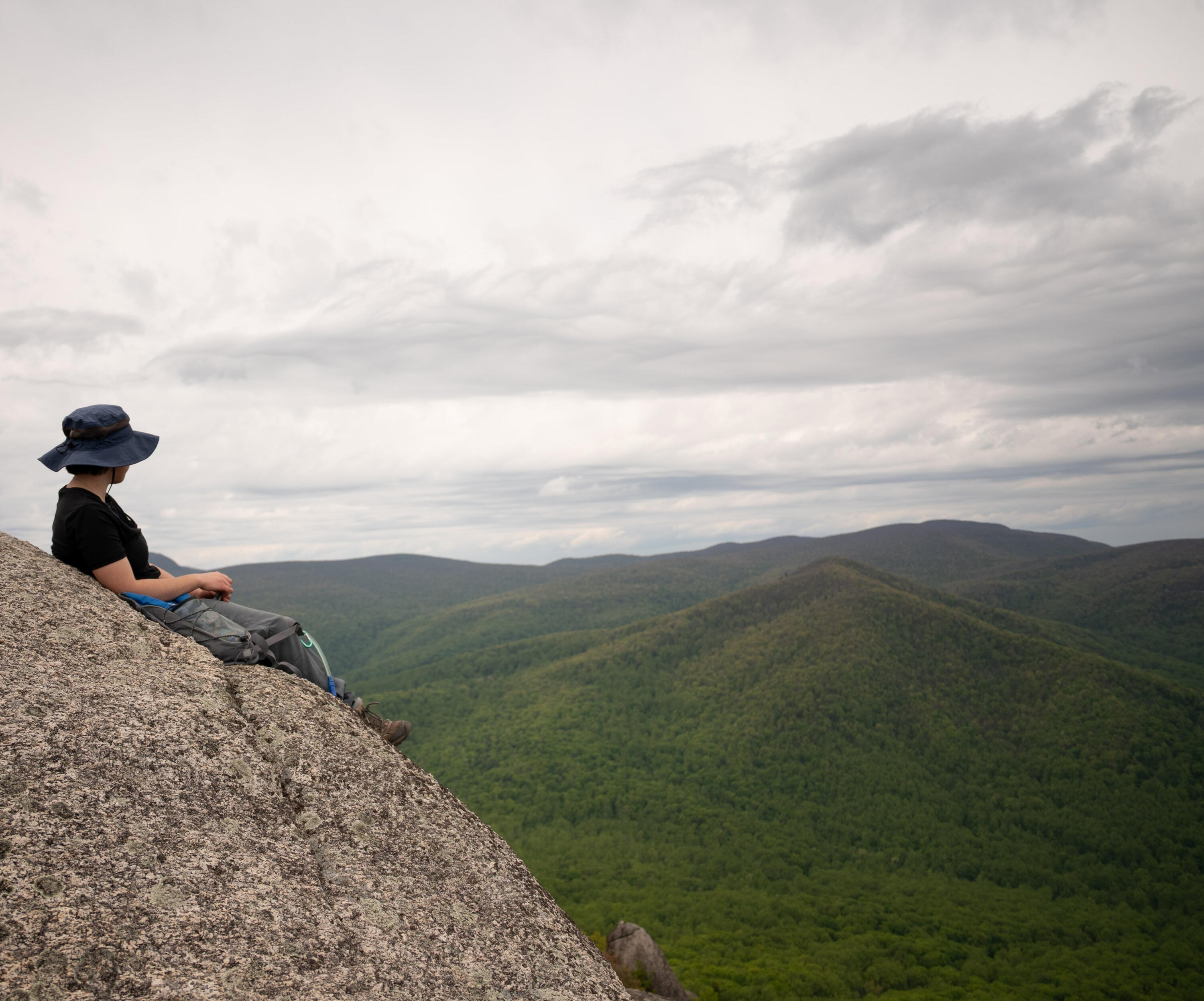 Looking at the Shenandoahs A hiker takes a break on top of a mountaintop boulder and looks out at the Shenandoah mountains